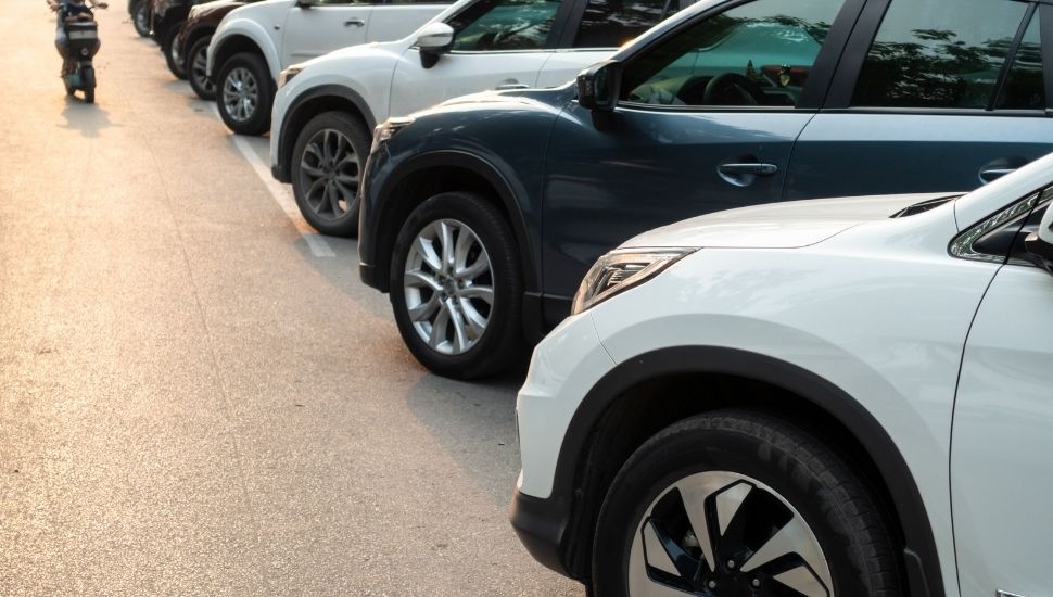 Camionetas SUV estacionadas en fila en un patio al aire libre con luz cálida de atardecer