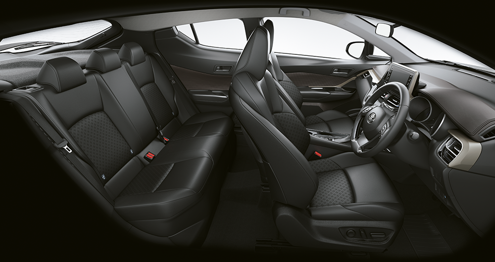 Interior Toyota C-HR con asientos de cuero negro, habitáculo lateral completo mostrando butacas delanteras y traseras