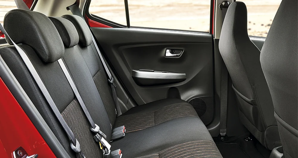 Asientos traseros de tela negra con cinturones de seguridad en interior de auto rojo