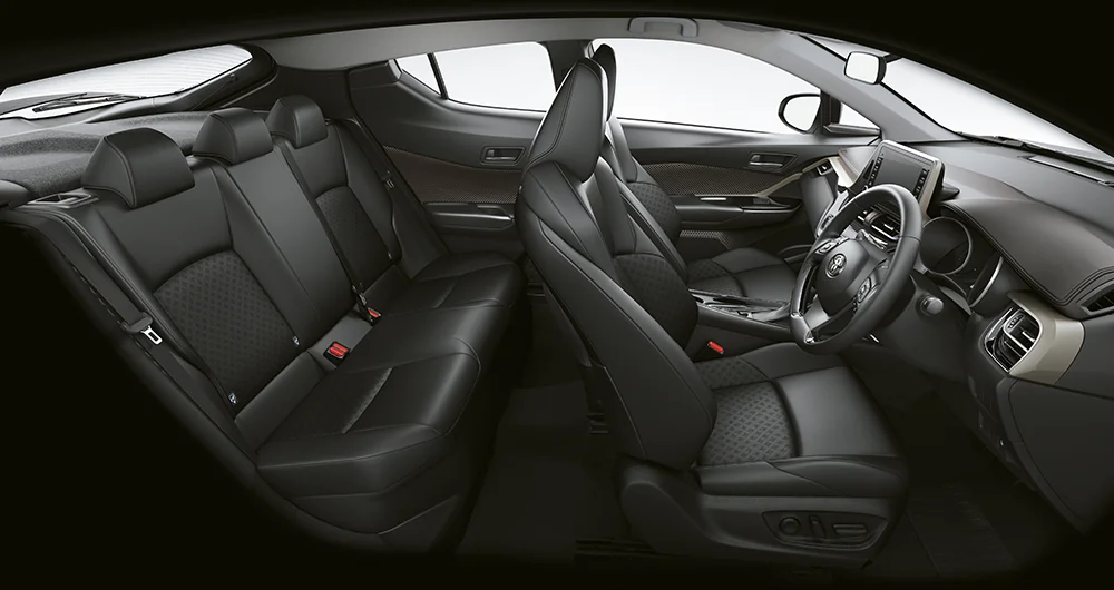 Interior Toyota C-HR con asientos de cuero negro, habitáculo lateral completo mostrando butacas delanteras y traseras