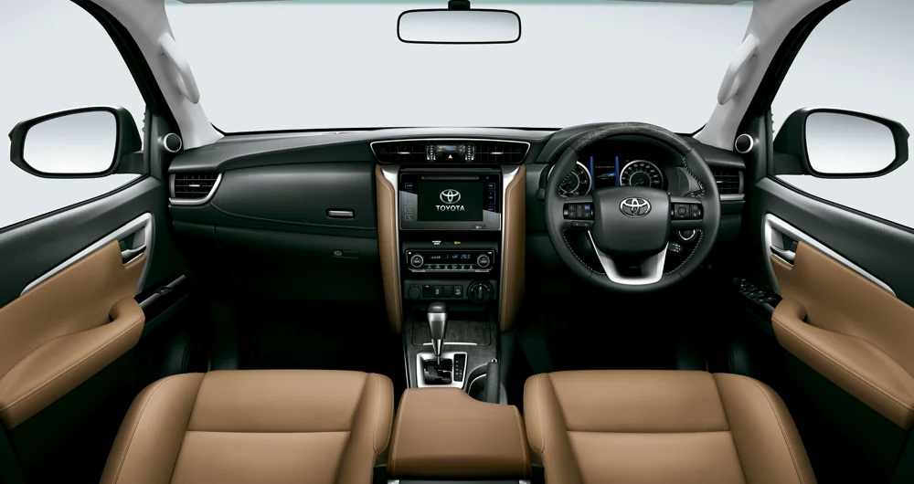 Interior Toyota Fortuner con tablero negro y marrón, pantalla táctil Toyota, volante y asientos de cuero camel