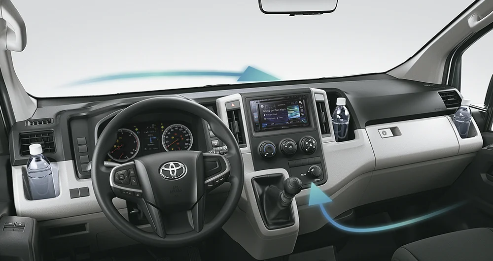 Tablero interior de Toyota con volante, pantalla central y portabotellas con flechas de ventilación