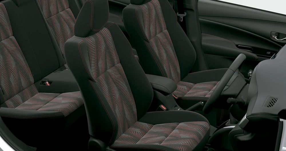 Interior de auto con cuatro asientos tapizados en tela negra y rojo con costuras decorativas