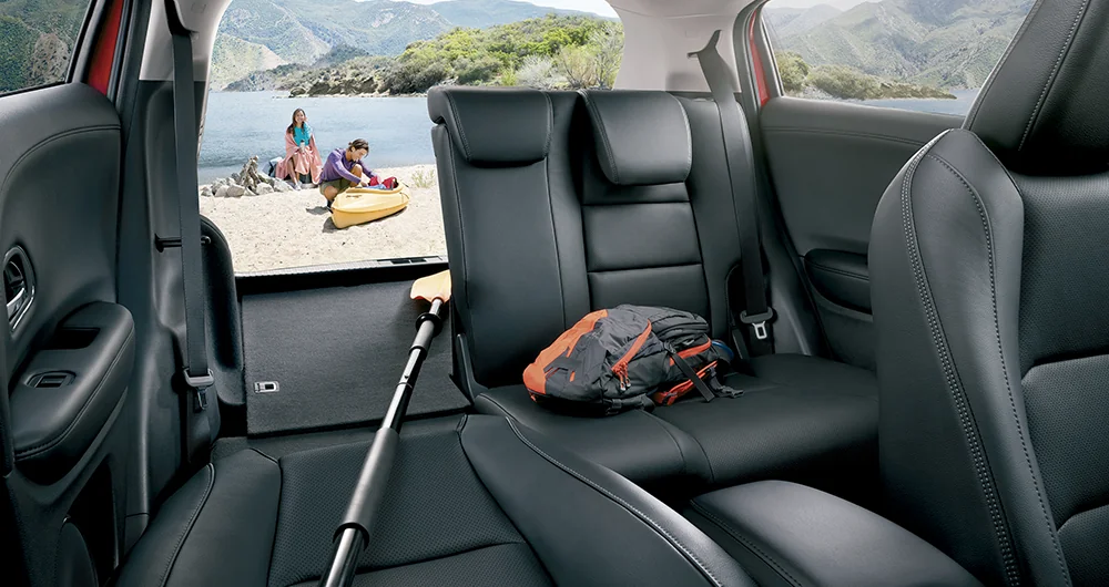 Interior trasero Honda HR-V con asientos en cuero negro y maletero abierto con mochila y remo
