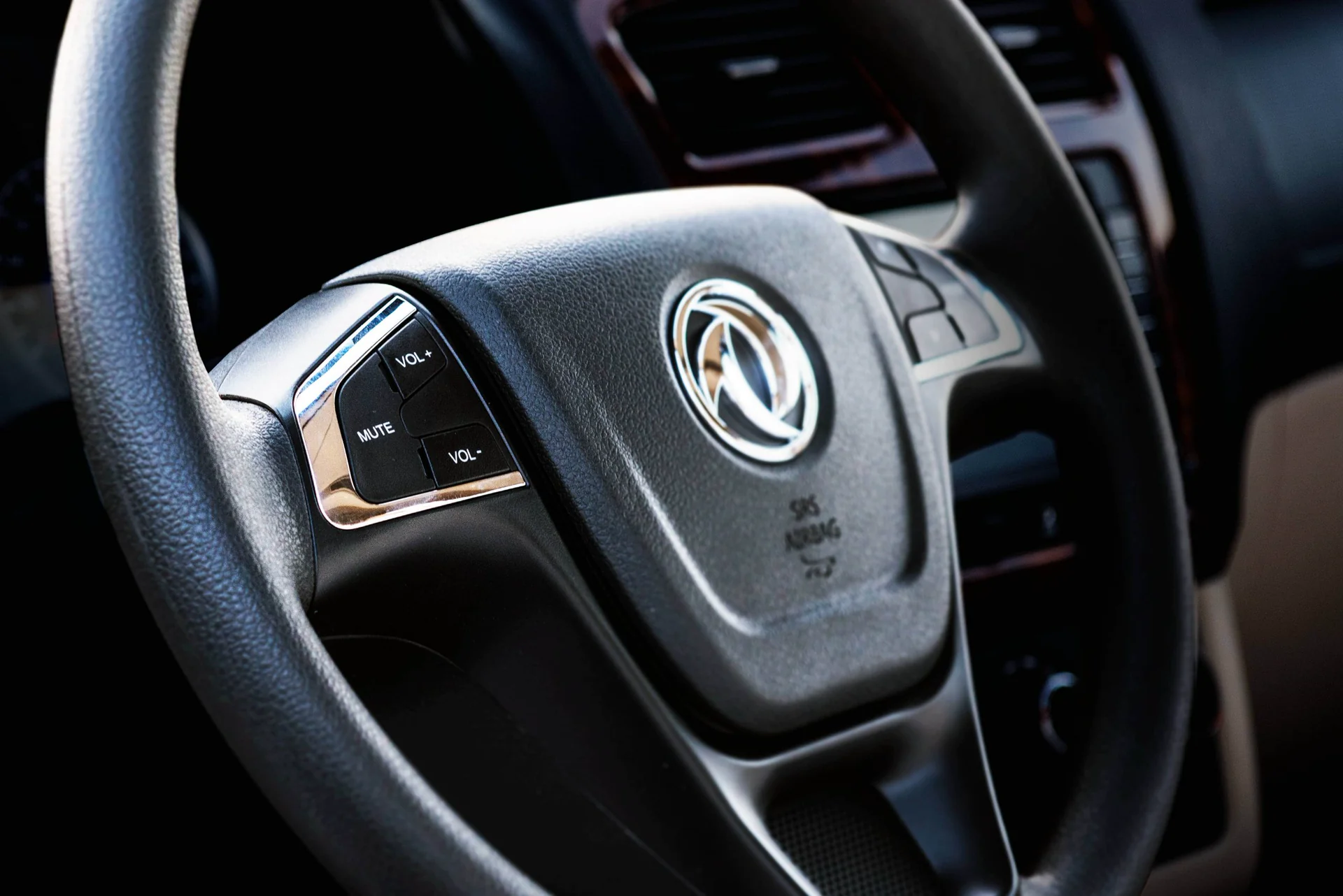 Volante del DFSK Glory 330 con controles de audio en el timón y logo de la marca al centro