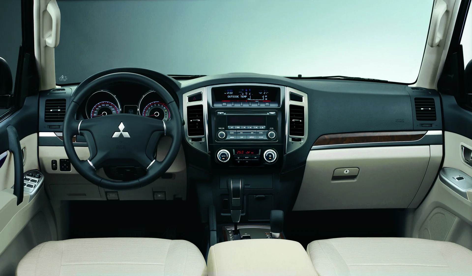 Tablero del Mitsubishi Montero con volante, sistema de audio y consola central en beige y negro