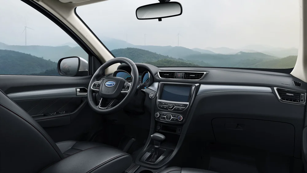 Interior del Karry K60J desde el asiento del conductor con pantalla central y vista a las montañas