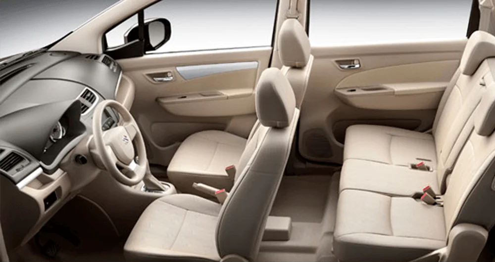 Interior del Suzuki New Ertiga con tres filas de asientos beige claros vistos lateralmente