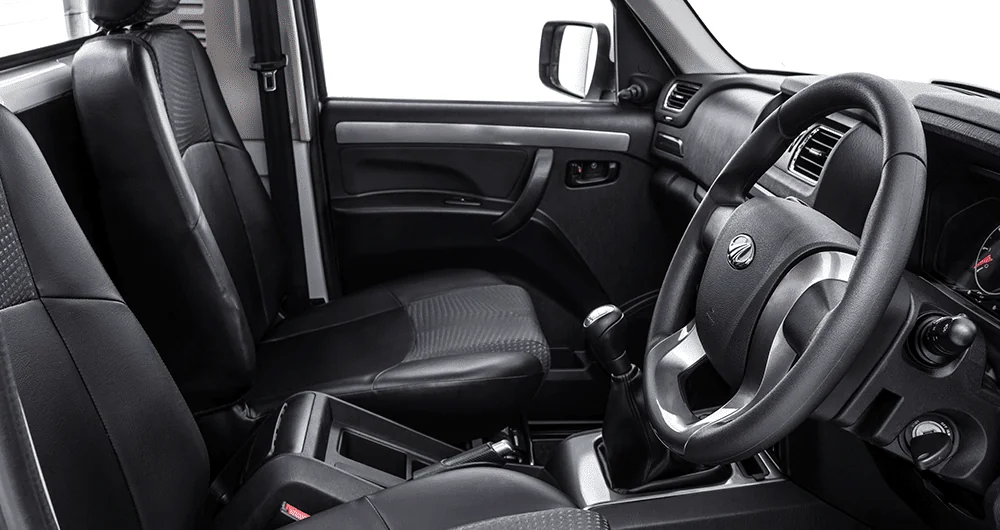 Interior lateral de camioneta con asientos de cuero negro, volante y tablero gris en cabina amplia